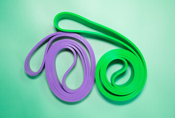 Fototapeta premium The concept of sports, fitness and a healthy lifestyle. Multicolored fitness rubber bands on a green background. Copy space .