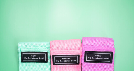 The concept of sports, fitness and a healthy lifestyle. Multicolored fitness rubber bands on a green background. Copy space .