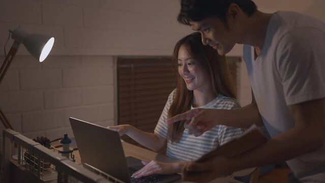 Asian young lovely couple overworking at home at dark night in bedroom. 