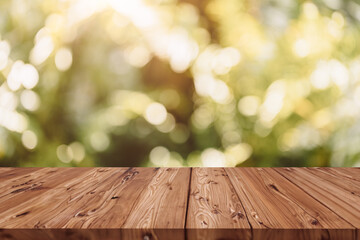Rustic wooden table on green bush blank old wood table top, blur green foliage park with sunlight...