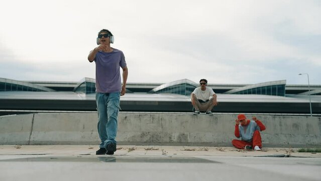 Group of asian break dancer perform street dance with multicultural friend support and moving hip hop music. Attractive handsome hipster practice b boy dance at street. Outdoor sport 2024. Sprightly.