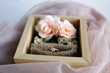 Wedding rings on a wooden box with floral decor lies. Wedding Accesories.