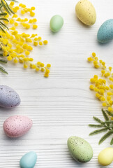 Colorful easter eggs  and mimosa flowers on wooden table.