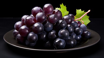 Fototapeta premium Grapes in a plate on a black background