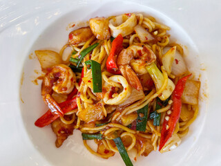 Closeup and top view fusion prawns and squids Stir Fried Chili Paste spaghetti in white ceramic plate.
