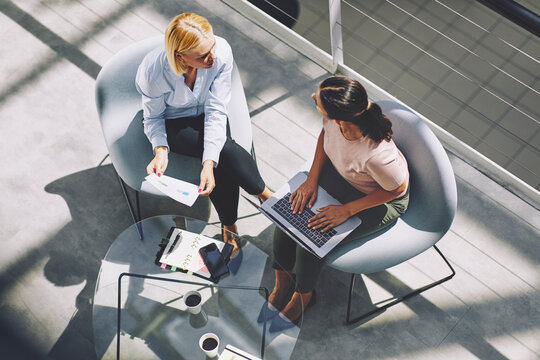 Businesswomen talking during a meeting while typing on a laptop