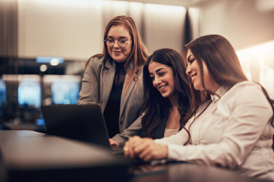 Smiling businesswomen working on a laptop together in a hotel lobby