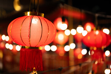 Close-up photo of many red Chinese lanterns hanging in a row at night. Has large, outstanding bokeh Waiting for the Chinese New Year festival in the Chinatown area of Asia.