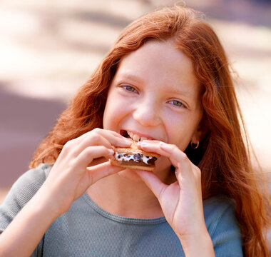 Child, eating and portrait with smores outdoor, camping and relax at barbecue with dessert or cookie. Happy, girl and hungry for biscuit with marshmallow in woods or forest on holiday or vacation