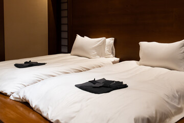 A serene double bedroom setup featuring plush white bedding and pillows with neatly folded...