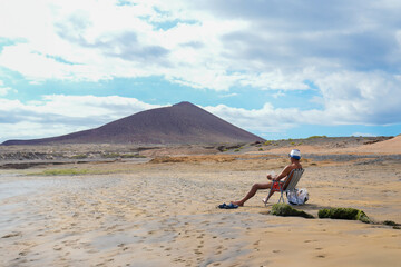 A man sits atop a surfboard on a beautiful sandy beach in El Medano, Tenerife.