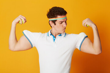 Tennis, sports and man flexing arms with fitness and workout on yellow background. Person, model and athlete with wellness, goofy or funny with confidence and proud with health, strong or competitive