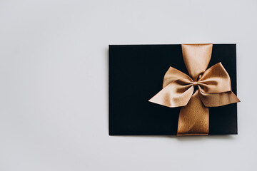 black envelope with a luxurious bow on a light background. free space for writing. an invitation, a present for Valentine's Day, for a wedding. romance and luxury