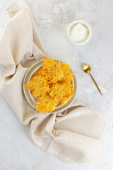 Crispy potato pancakes, draniki, Latkes or Levivot with sour cream in a plate. Hanukkah food. Vertical orientation, top view.