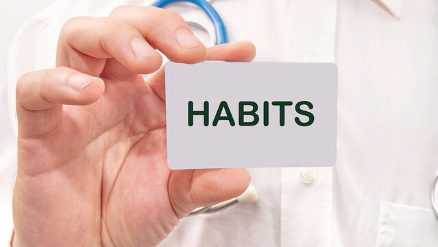 HABITS word on the card in a man's hand on the background of a white shirt