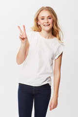 Young woman, peace sign and portrait in studio for happiness, positive and funky in casual fashion. American model, smile and face with blond hair in trendy jeans, emoji and gen z by white background