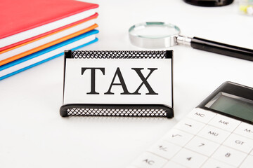 TAX text on a business card next to office supplies on a white background
