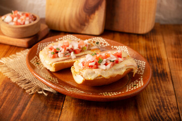 Molletes. Mexican recipe based on bolillo bread split lengthwise, spread with refried beans and gratin cheese, adding pico de gallo sauce and some protein such as ham, bacon or chorizo.