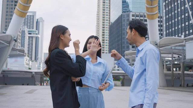 Asian young business people say hi and doing high five outdoor in city. 