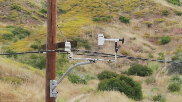 Modern aerovane or anemometer measuring wind speed and direction in Santa Monica mountains, Los Angeles suburban, California, USA. Wind speed meter rotating in on power pillar by the wind, 4k footage