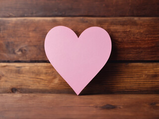 heart shape made of pink paper on wooden background with empty space in the middle for text