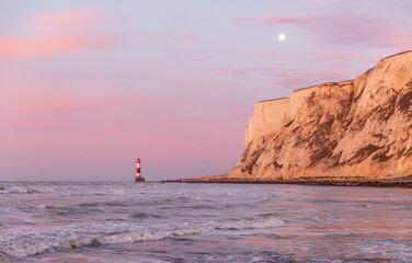 Sunrise and moonset at beachy head lighthouse during low tide east Sussex coast south east England...