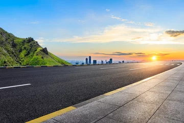 Fotobehang Asphalt highway road and green mountain with city skyline at sunset © ABCDstock