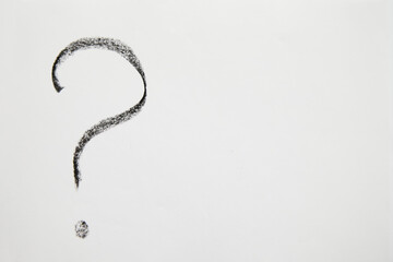 A handwritten question mark in black chalk on a white background. Business concept, doubts, insecurities