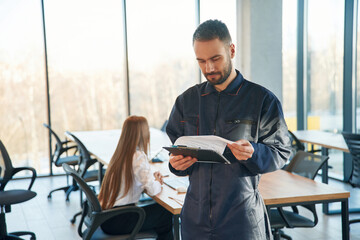 Repairman is standing in the office, employees behind