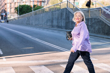 senior woman smiling happy crossing a city street by pedestrian crossing, concept of elderly people...