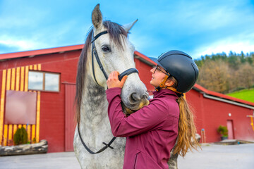 Jockey caressing a horse head on a equestrian center