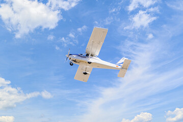 Single engine ultralight plane flying in the blue sky with white clouds	
