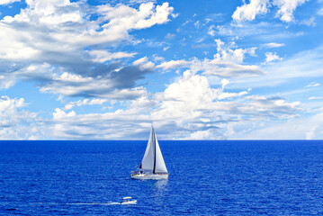 Boat, sailboat sailing on the beach of Mallorca under a blue sky with white clouds	