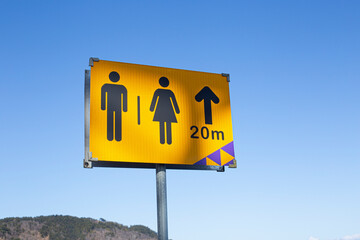 male and female icon yellow road sign on sky background