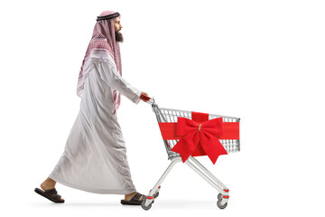 Full length profile shot of a saudi arab man pushing an empty shopping cart with red ribbon bow