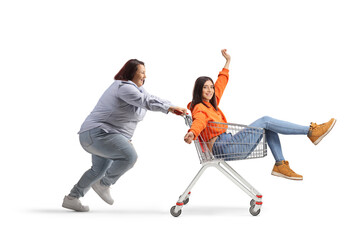 Corpulent woman pushing slim young woman inside a shopping cart