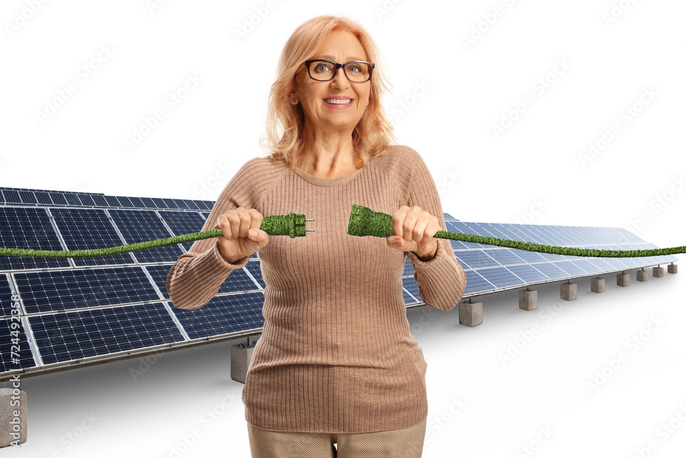 Wall mural smiling mature woman at a solar field plugging in green electric cables