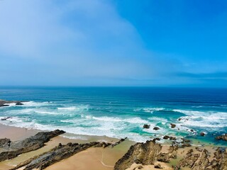 Fototapeta na wymiar Rocky ocean coast, ocean bay with rocky coast and sand beach, blue sky, no people