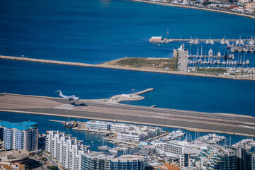 Gibraltar, Britain - January 24, 2024 - A plane landing on a narrow runway by the sea, near a...