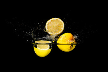 Three pieces of sliced lemons falling into water with a black background creating a splash