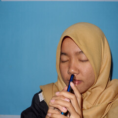 An Asian woman wearing a headscarf is playing a smart phone.