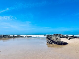 Fototapeta premium Rocky ocean coast, ocean bay with rocky coast and sand beach, blue sky, no people