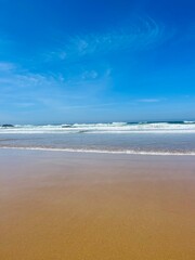 Fototapeta na wymiar Blue sea horizon, sandy coast, waved, blue sky
