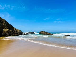 Fototapeta premium Rocky ocean coast, ocean bay with rocky coast and sand beach, blue sky, no people