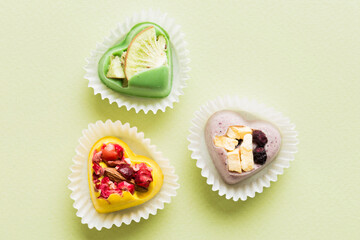 chocolate sweets in the form of a heart with fruits and nuts on a colored background. top view with space for text, holiday concept