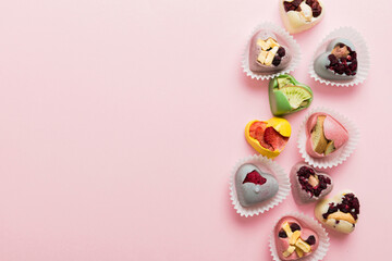 chocolate sweets in the form of a heart with fruits and nuts on a colored background. top view with space for text, holiday concept