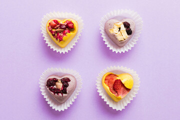 chocolate sweets in the form of a heart with fruits and nuts on a colored background. top view with space for text, holiday concept