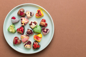 Plate with different chocolate on colored background. Assortment of fine chocolates top view vith copy space Health and obesity concept