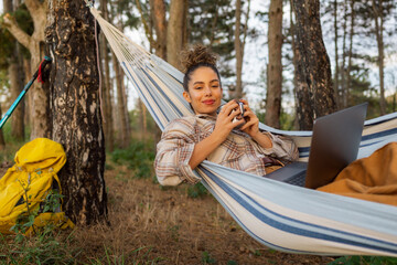 Enjoying a cup of tea in her hammock, the freelancer uses her laptop to combine work and nature.