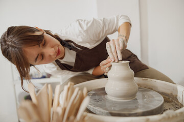 Professional female artisan shaping clay bowl in pottery studio. Ceramics art concept